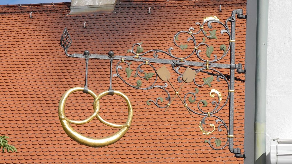 Schmiedeeisernes Bäckerei-Schild in Brezelform an einer Hauswand