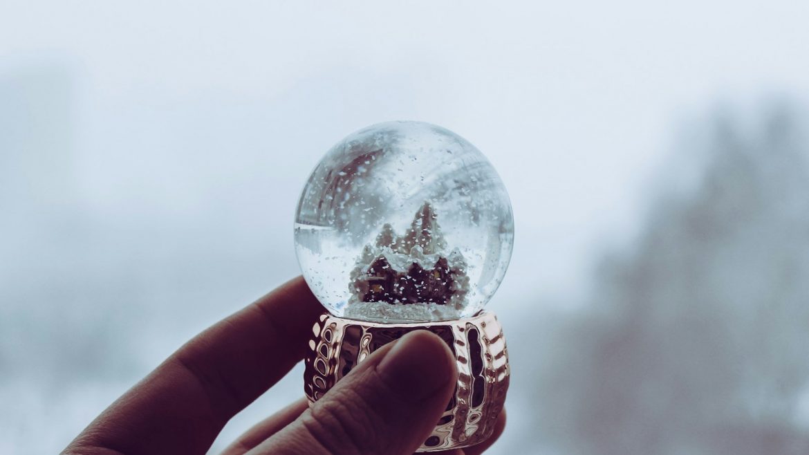 Hand hält eine Schneekugel als Weihnachtsgeschenk für Kunden
